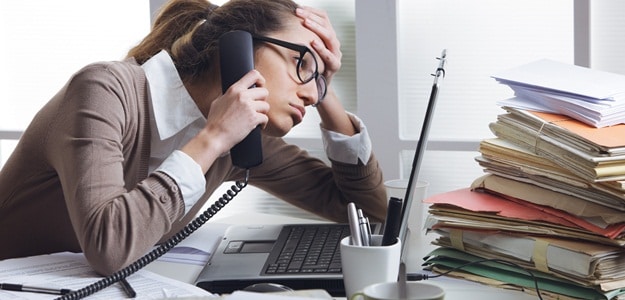 A stressed business woman looks tired she answer telephones in her office